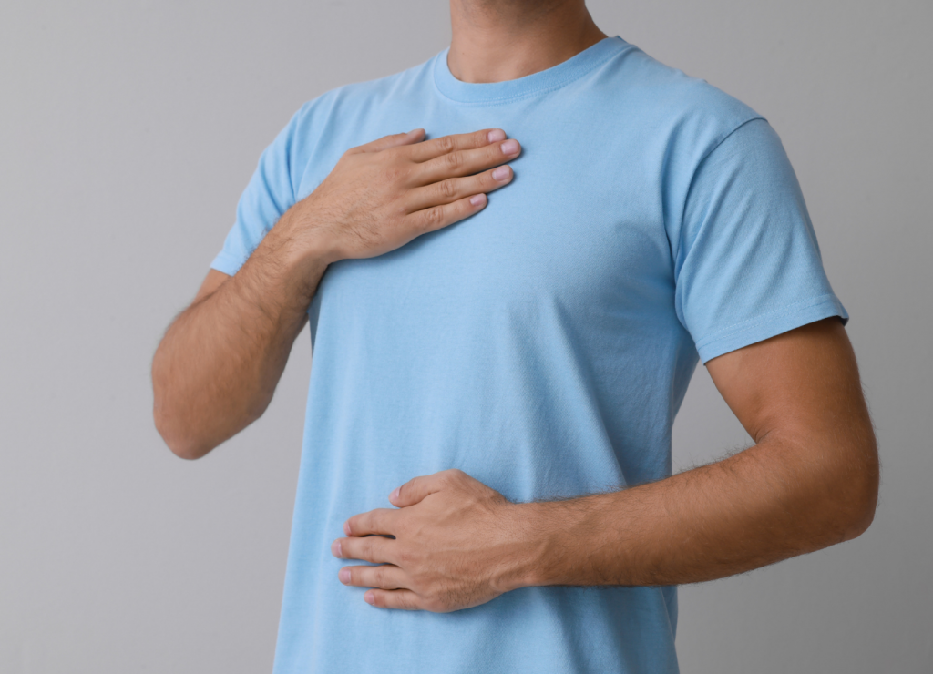 A man with his hands resting on his chest and stomach, conveying a sense of discomfort or distress, possibly related to digestive issues or abdominal discomfort.